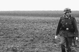 A lone solider traipsing across an open field.