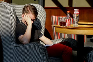 A tired gentleman trying to read a book but instead napping