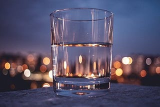 A cup of water with a city view on the background