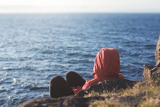 on island, facing water, wearing red head covering