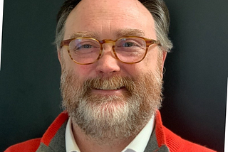 A balding middle-aged man with glasses and a beard.