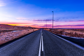 A paved road extending toward a beautiful sunset horizon