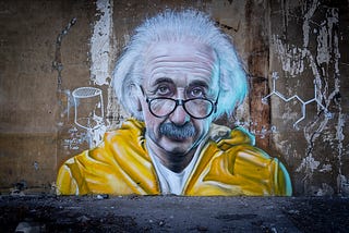 A graffiti portrait of Albert Einstein in a yellow hoodie, with glasses.