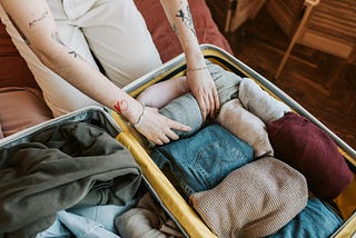 Image of person packing suitcase with clothes neatly rolled