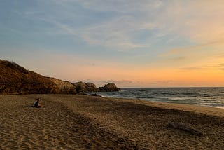 Couple meditating on the beach at sunset in Oaxaca, Mexico