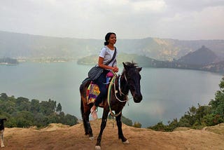 Nardos riding a horse with a beautiful lake in the background.