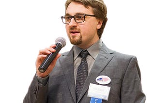 Michael O’Shea speaks into a microphone.