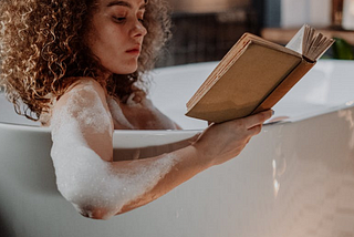 Woman relaxing in tub while reading a book