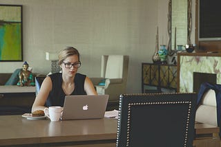 Someone working from home at their dining room table (PS: does anyone’s home really look like this? 🙂)