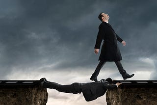 A man walking across another man who is bridging a gap
