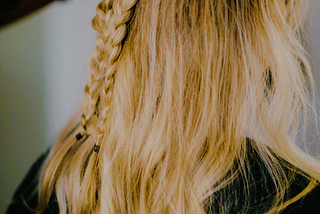 A woman getting her hair done; blond hair with a braid