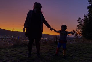 Mother and son holding hands and telling tales with the sunset in the background.