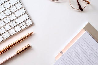 A laptop, pen, notebook, and spectacles.