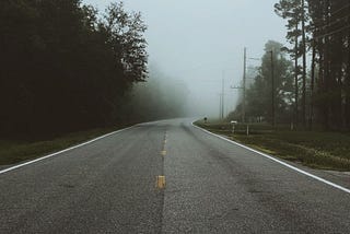 a straight road going to a foggy place