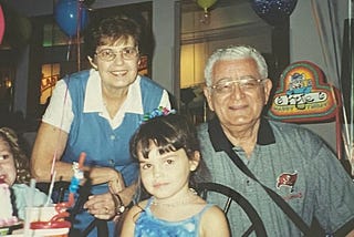 The author as a young girl, with her grandparents behind her, posing for a photo at her birthday party.