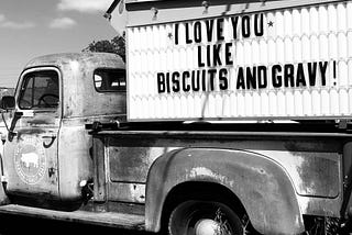 An old pickup truck with a sign saying I Love You Like Biscuits and Gravy!