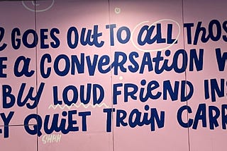 Picture of a wall with the words “This wall goes out to all those about to havea conversation with an incredibly loud friend inside and overly quiet train carriage.”