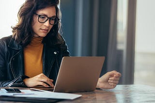 Asian woman working laptop at contemporary office in casual attire