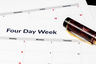 A red marbled pen sits on top of a calendar with the heading “Four Day Week.”