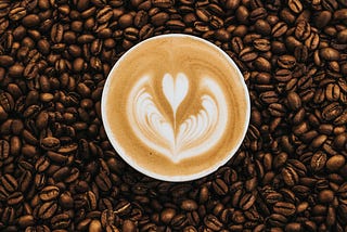 Coffee in a cup is placed on spread coffee beans.