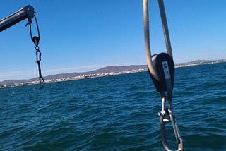 Blocks and tackle hang from davits on a sailboat’s stern