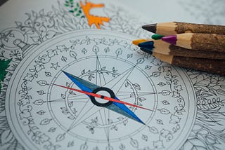 A partially colored in picture of a compass in a coloring book.