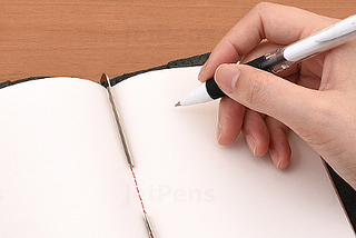 Hand holding a pen over a blank note book