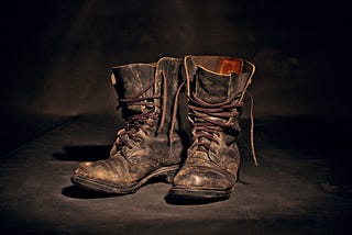 A very worn old pair of leather boots with cheap soles.