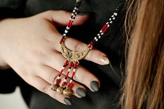 With the back of her hand, Alida holds a red, black, white, and gold necklace blessed by a Santero and honoring the West African orisha Eleggua.