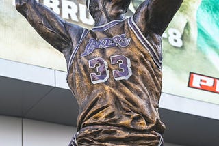 Bronze statue of Kareem Abdul-Jabbar wearing his Lakers jersey taking a shot