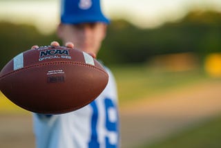 football player holding up an ncaa football