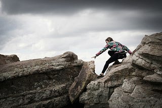 woman climbing on rocks during daytime