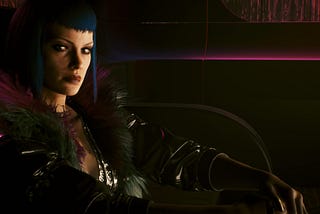 Evelyn Parker in a private room at Lizzie’s bar in Cyberpunk 2077. Evelyn is white, slender, with light eyes, a freckled face, and a signature sci fi bob with short little bangs, deep blue in color.