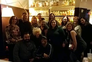 The Arts Education council is standing in a group photo at a restaurant during their 2020 retreat
