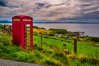A lonely iconic red phone booth overlooking the water on the Isle of Skye