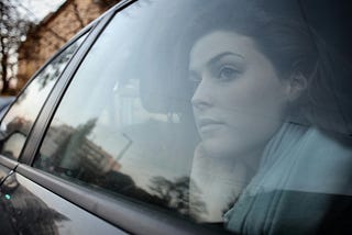 Woman gazing out a car window, lost in thought during a quiet drive — a moment of reflection on life’s shifting seasons.