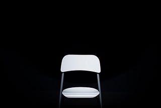 Image of a white folding chair on a black backround