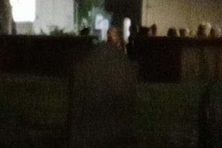 A graveyard in Salem, Massachusetts at night, featuring an image of a female ghost.