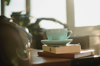 Coffee mug balanced on book and journal. Image courtesy of Samson Katt @ Pexels