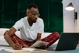 Man Sitting on a Bed Using Gadgets