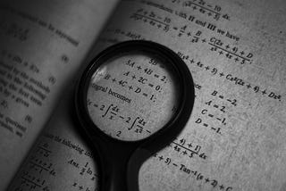 A magnifying glass zooming in on a math formula of a book.