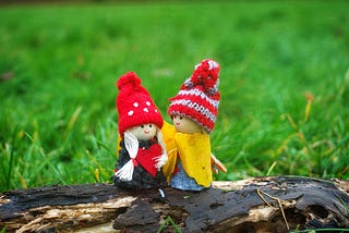 two wooden dolls on a log