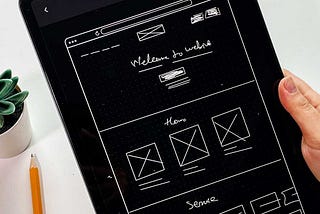 A hand holding a tablet device with a wireframe in it