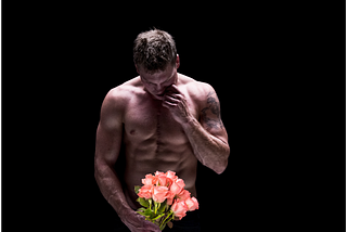 topless man holding roses against a black background; alt-text for “I am the Guy in the Contemporary Romance Novel & I’ll wait for you”