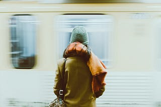 Lady on a plateform waiting for a metro to stop.