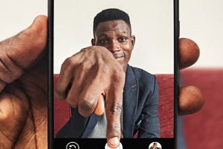 A man reaching his hand out of the smartphone screen to press and hold the smartphone’s button