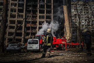 A fireman standing in front of a burnt building