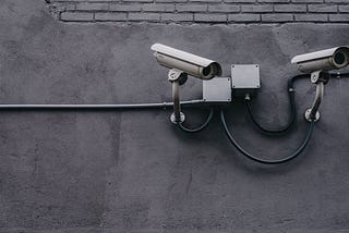 Two Gray Bullet Security Cameras On A Wall