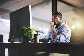 Man focusing intently on a computer screen at a desk in the early morning