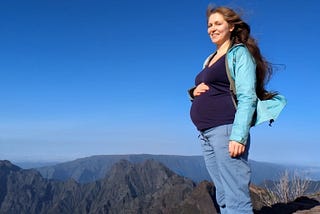 The author, pregnant, standing on a mountaintop